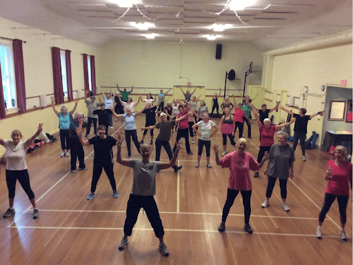 Group exercise class at Fanny Bay Community Hall with diverse participants.