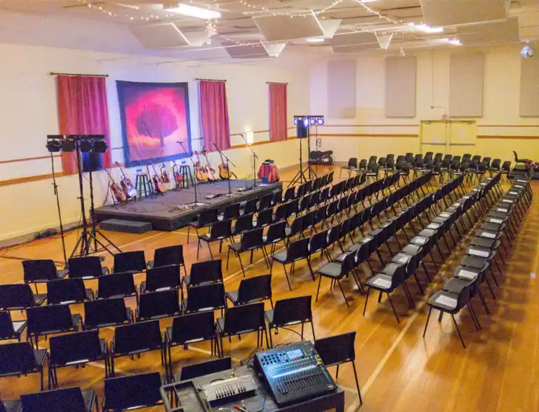 Event space with stage, musical instruments, and seating at Fanny Bay Community Association.