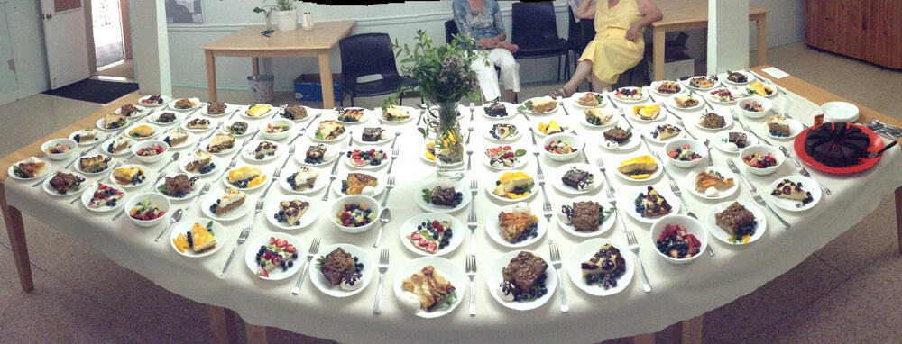 Community food event with a large table of diverse dishes at Fanny Bay.