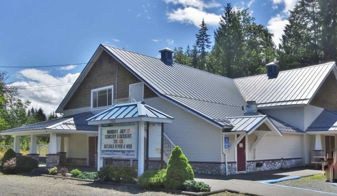 Fanny Bay Community Association building with a metal roof and surrounding greenery.